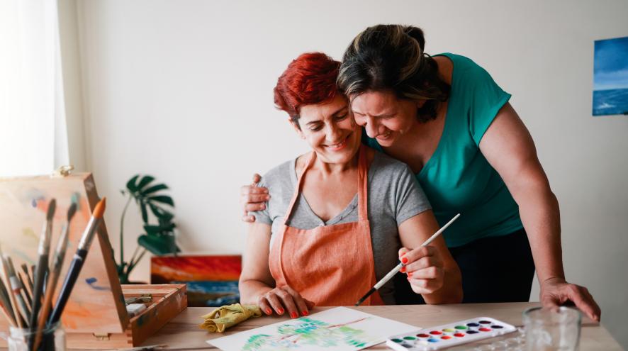 Couple side-hugging while painting together 